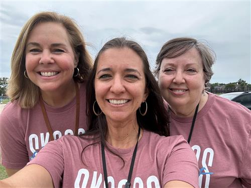 The Skaggs 2nd grade team smiling in a field and wearing Skaggs spirit shirts